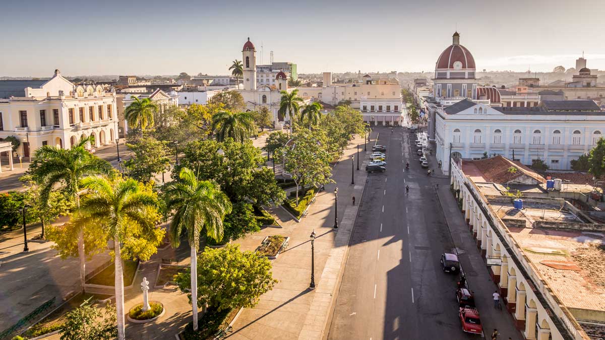 View of Parque José Martí, Cienfuegos – Photo: Shutterstock small city park with palm trees and streets with parked cars